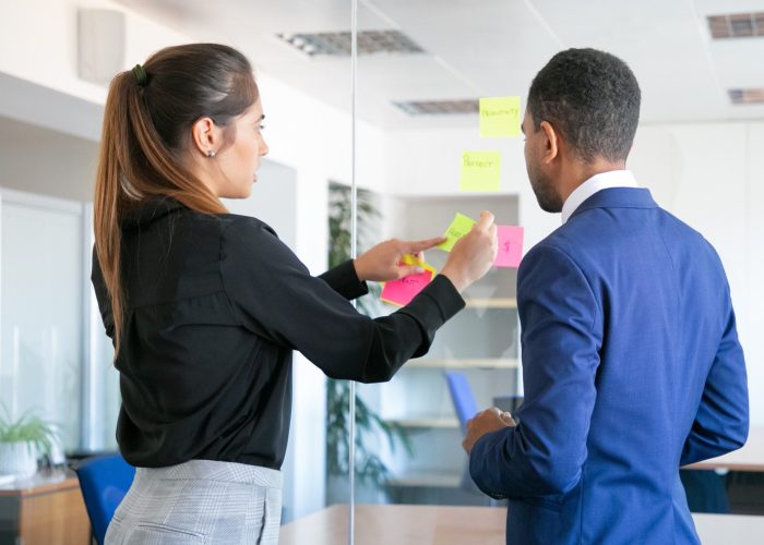 Mulher e Homem alinhando tarefas com post-ot